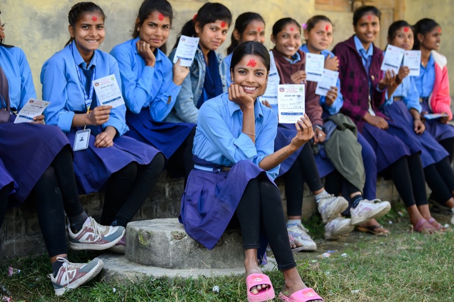 Schoolgirls in Nepal holding HPV vaccination cards